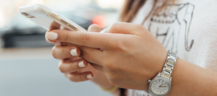 Nainen pitelee puhelinta kaksin käsin.